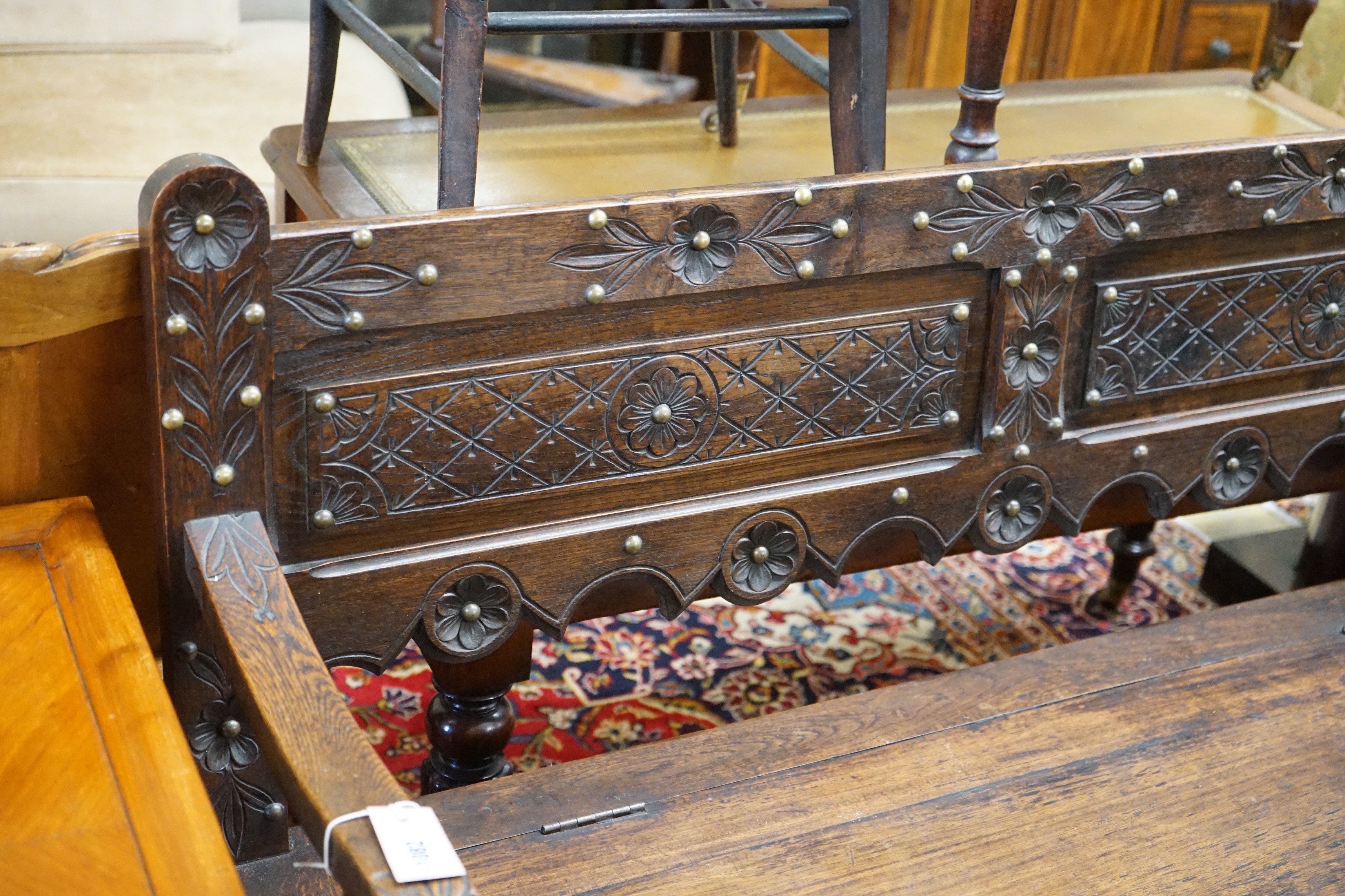 An 18th century style brass studded carved oak box seat settle, length 136cm, depth 40cm, height 93cm